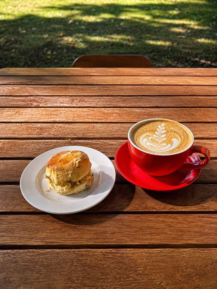 A latte and a scone served at an outdoor table