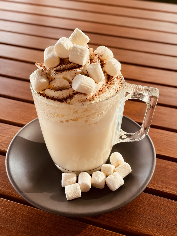 Hot drink topped with marshmallows on a saucer