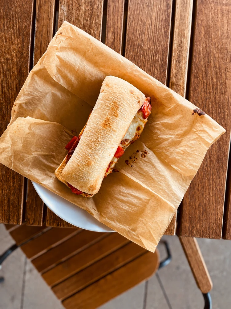 Ciabatta sandwich served on paper at a wooden table